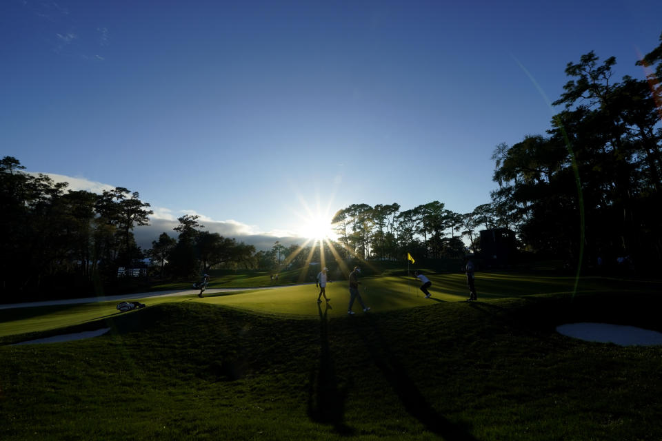 Golfers putt on the 15th green as the sun sets during the first round of play in the Players Championship golf tournament Thursday, March 10, 2022, in Ponte Vedra Beach, Fla. (AP Photo/Gerald Herbert)