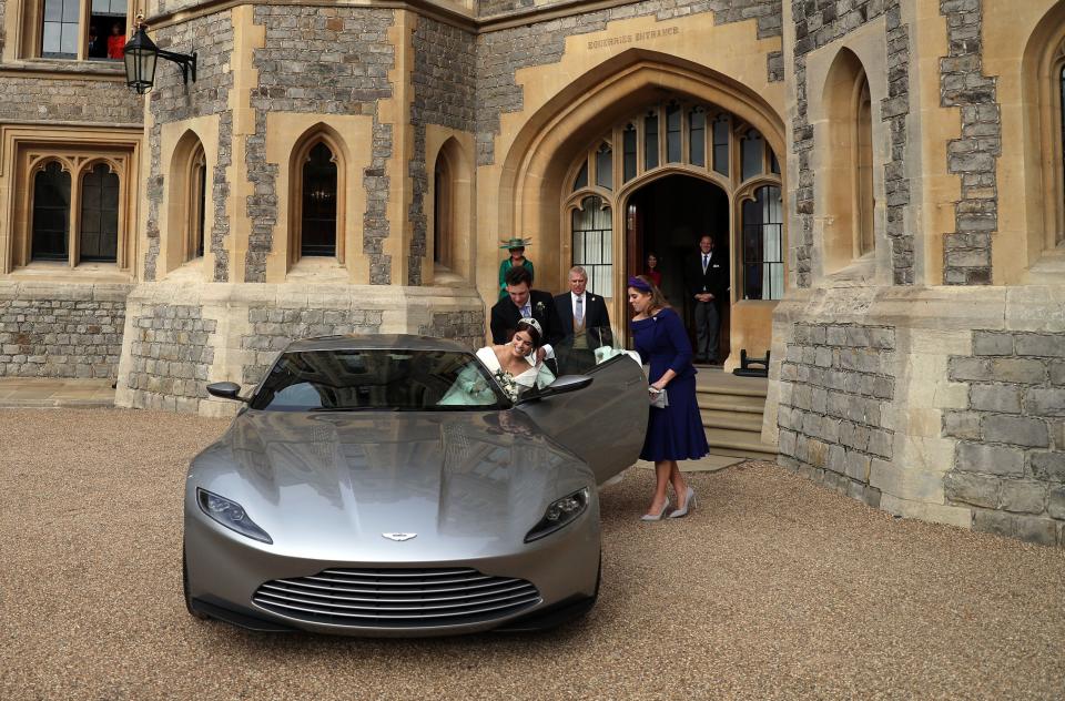 Britain's Princess Eugenie of York is helped into an Aston Martin DB10 by her sister Britain's Princess Beatrice of York, as she leaves with her Jack Brooksbank for Royal Lodge in Windsor Great Park, Windsor on October 12, 2018 after their wedding ceremony. (Photo by Steve Parsons / POOL / AFP)        (Photo credit should read STEVE PARSONS/AFP via Getty Images)