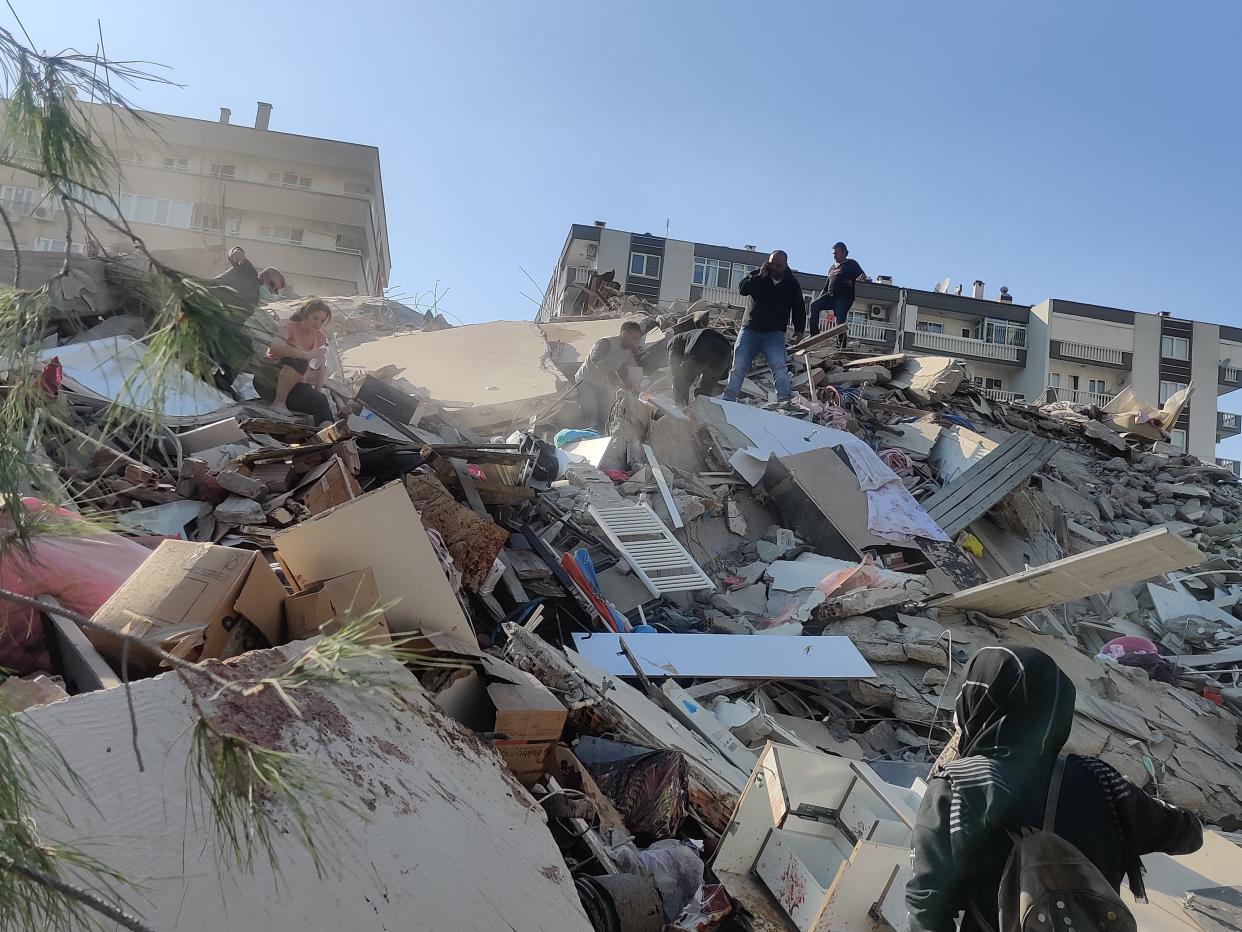 Citizens are seen on a ruin of destroyed building right in Izmir, Turkey (Anadolu Agency via Getty Images)