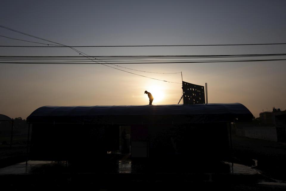 A man washes with soap and water the roof of his restaurant as a precautionary measure amid the spread of the new coronavirus in San Andres Mixquic, Mexico, Monday, March 30, 2020. (AP Photo/Fernando Llano)