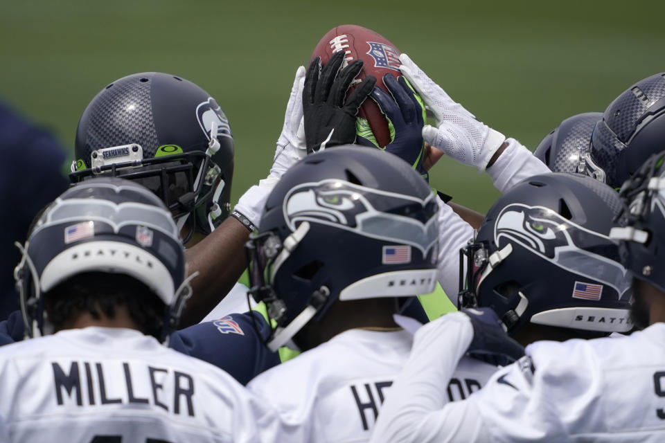 Seattle Seahawks defensive players touch the football during a huddle at NFL football practice Tuesday, June 15, 2021, in Renton, Wash. (AP Photo/Ted S. Warren)