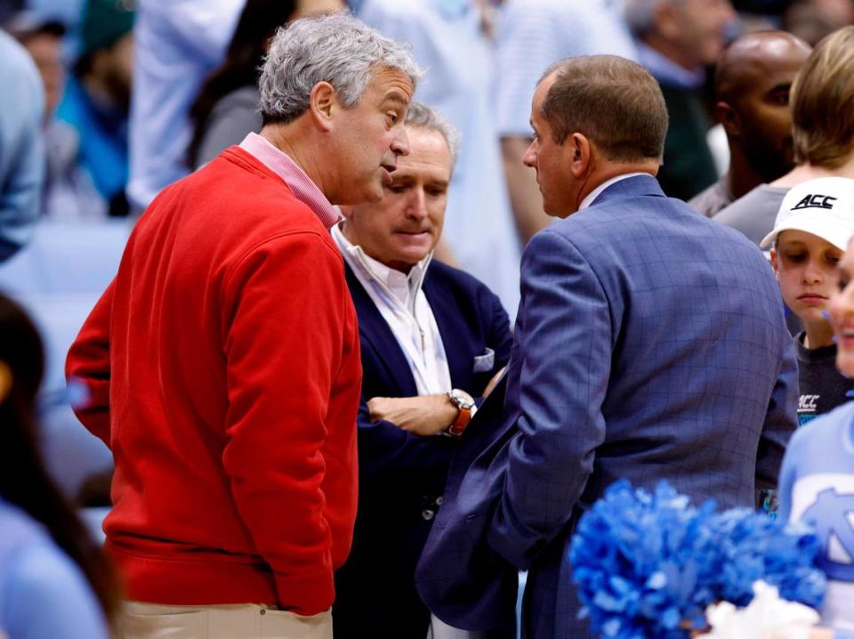 N.C. State athletic director Boo Corrigan, left, and North Carolina athletic director Bubba Cunningham, center, talk with ACC Commissioner Jim Phillips before N.C. State’s game against UNC at the Smith Center in Chapel Hill, N.C., on Jan. 21, 2023.