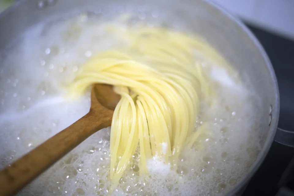 Boiled water and spaghetti noodles in a pot.