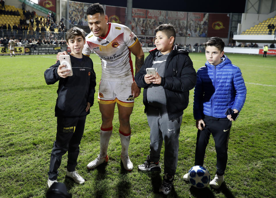 Catalans Dragons Israel Folau has his photo taken with young fans after the Super League rugby match between Catalans Dragons and Castleford Tigers at Stade Gilbert Brutus in Perpignan, France, Saturday, Feb. 15, 2020. (AP Photo/Joan Monfort)