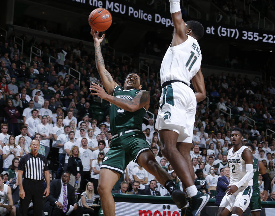 Binghamton's Sam Sessions, left, shoots next to Michigan State's Aaron Henry during the first half of an NCAA college basketball game Sunday, Nov. 10, 2019, in East Lansing, Mich. (AP Photo/Al Goldis)