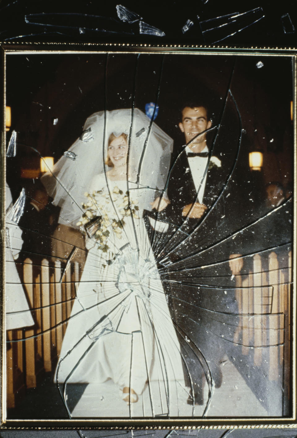 A wedding photo of a bride and groom, center, with cracked glass over the image