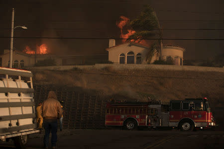 A fire truck heads to another call as a house burns during a wind driven wildfire in Ventura. REUTERS/Mike Blake