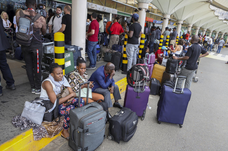 Passengers wait with their luggage outside the terminal at Jomo Kenyatta International Airport in Nairobi, Kenya on Saturday, Nov. 5, 2022. Pilots working for Kenya's national airline Kenya Airways have been on strike for three days over a demand to honor a retirement savings plan, and it is estimated to be costing millions of dollars in losses daily. (AP Photo)