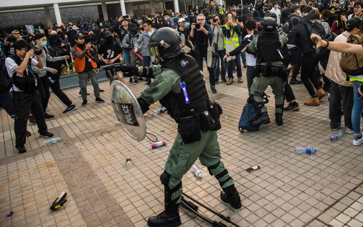 A police officer points a pistol at protesters during a rally in Hong Kong in December 2019 to show support for the Uighur Muslim minority in China - Dale de la Rey/AFP