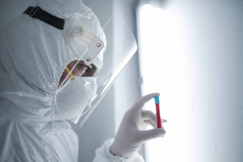 in a chemistry lab, a male researcher holds a tube with the coronavirus virus