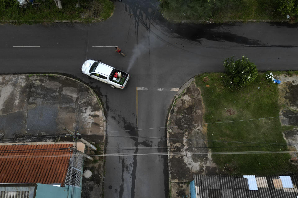 A young man rides his bike alongside a public health vehicle spraying insecticide during a fumigation campaign against dengue-promoting mosquitoes, in the Santa Maria neighborhood of Brasilia, Brazil, Tuesday, Jan. 23, 2024. (AP Photo/Eraldo Peres)