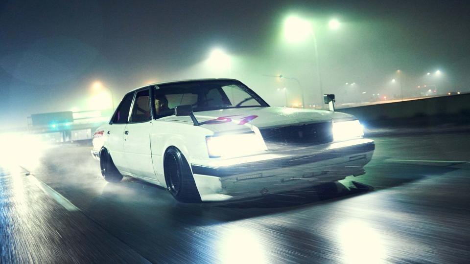 custom car drives at night on wet road