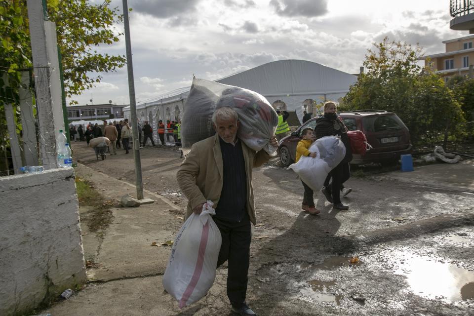 People carry clothes and other supplies distributed by authorities in Thumane, western Albania, Friday, Nov. 29, 2019. The operation to find survivors and recover bodies from Albania's deadly earthquake was winding down Friday as the death toll climbed to 49. (AP Photo/Visar Kryeziu)