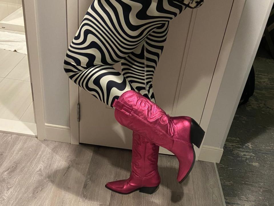 Someone wearing pink cowboy boots paired with black and white pants