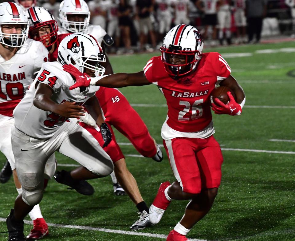 Ty Brown (26) stiff-arms his way past the Colerain defense of Fernando Roland (54) for a La Salle first down at Lancer Stadium, Aug. 18, 2023.