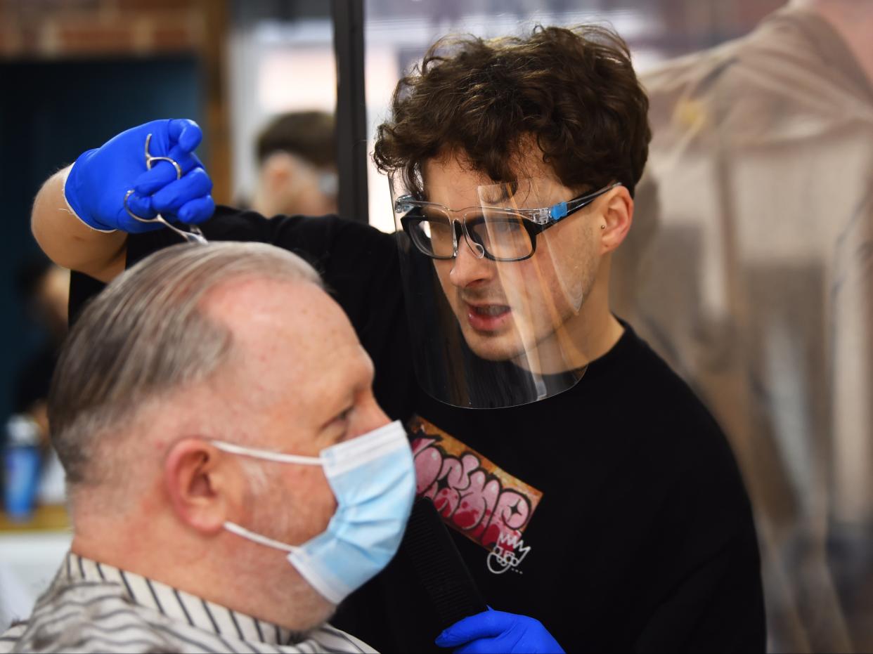 A man wearing a mask has his hair cut at The Men’s Den Barber Shop in Leek, England (Getty Images)