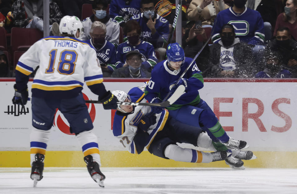 Vancouver Canucks' Elias Pettersson, back right, of Sweden, checks St. Louis Blues' Niko Mikkola, of Finland, during the third period of an NHL hockey game in Vancouver, British Columbia, Sunday, Jan. 23, 2022. (Darryl Dyck/The Canadian Press via AP)