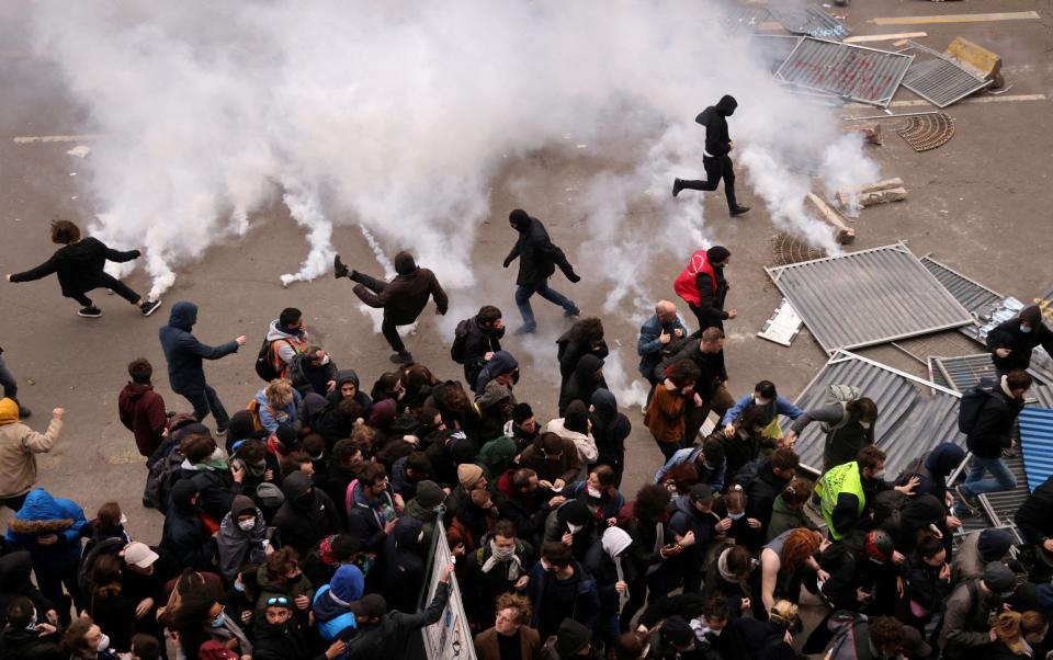 Protesters throw tear gas canisters back amid clashes during a demonstration - Nacho Doce/Reuters