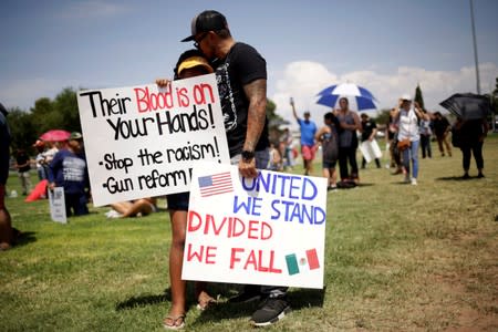 FILE PHOTO: People embrace while holding placards during a rally against the visit of U.S. President Donald Trump after last weekend's shooting at a Walmart store, in El Paso