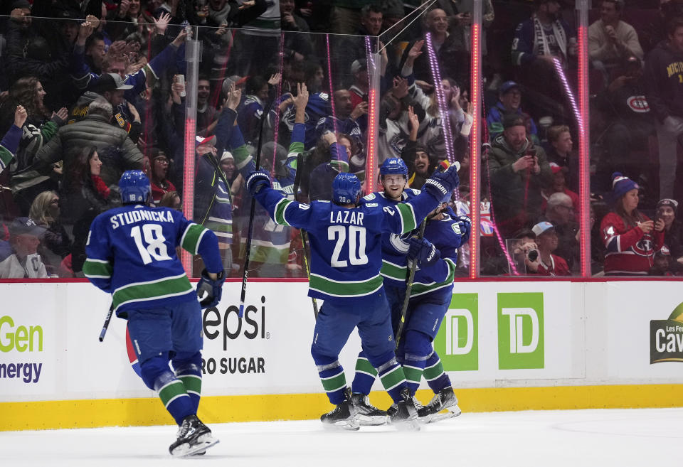 Vancouver Canucks' Elias Pettersson, back, of Sweden, Curtis Lazar (20), Quinn Hughes, back right, and Jack Studnicka (18) celebrate Pettersson's winning goal against the Montreal Canadiens during overtime in an NHL hockey game in Vancouver, British Columbia, Monday, Dec. 5, 2022. (Darryl Dyck/The Canadian Press via AP)