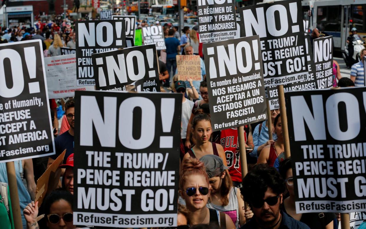 Protesters hold signs against Trump and Pence during a march against white nationalism in New York City - REUTERS