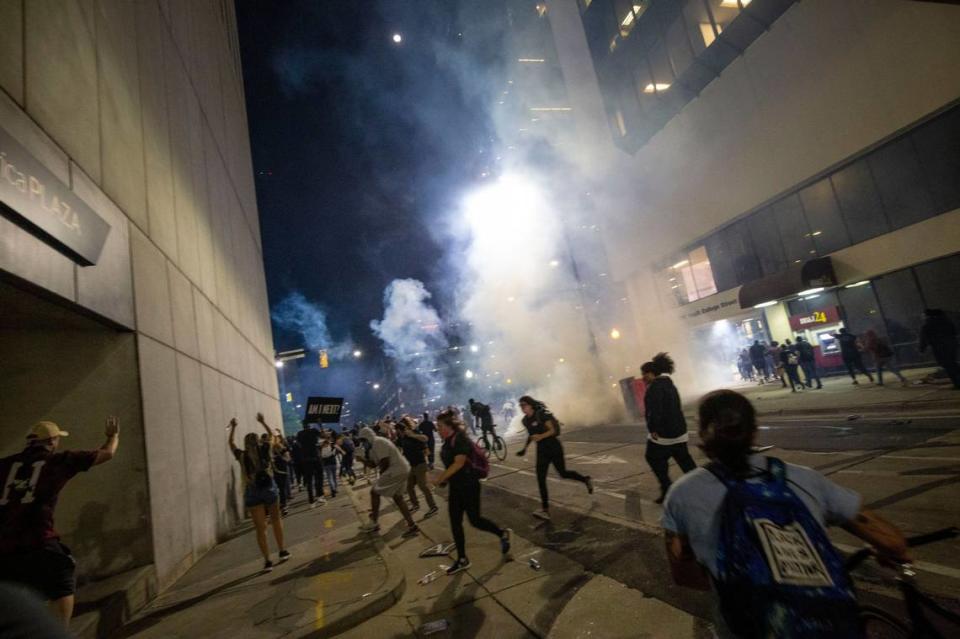 Protesters scramble on 4th Street as police fire chemical agents on either side of the marchers in uptown Charlotte, NC on Tuesday, June 2, 2020. A new class action lawsuit seeks millions in damages for the hundreds of protesters trapped in a police tactic known as kettling.