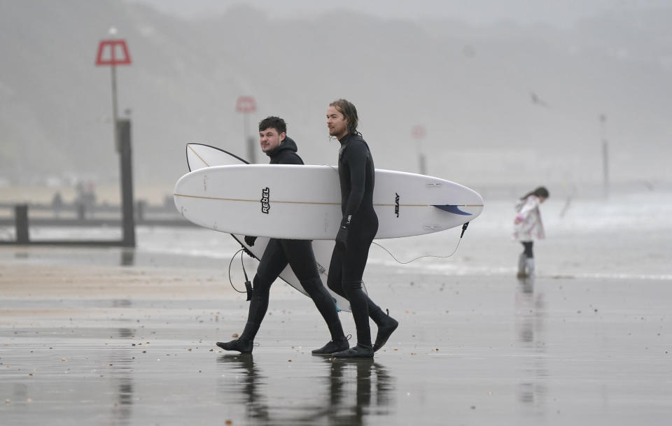 Two surfers walk out of the sea off of Bournemouth beach in Dorset. The UK could see the mildest New Year's Eve on record, with sunshine in some areas, after what is likely to be one of the dullest Decembers ever. But despite the sun, revellers in some parts of the UK will have to brace for heavy showers in the evening. Picture date: Friday December 31, 2021. (Photo by Andrew Matthews/PA Images via Getty Images)