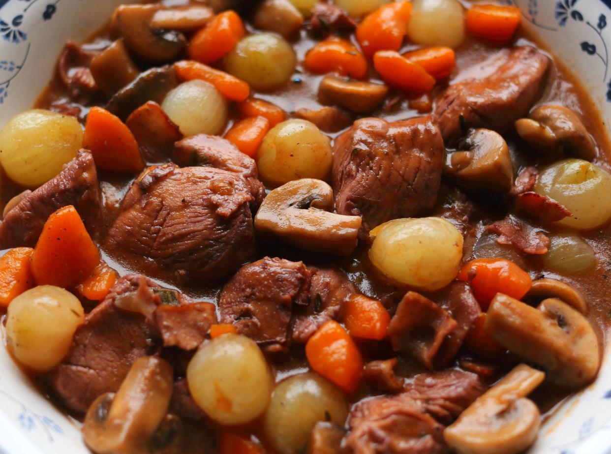 Coq au Vin. Typical, French dish of chicken in a red Burgundy wine sauce with mushrooms, carrots, pearl onions or shallots and bacon. (selective focus)