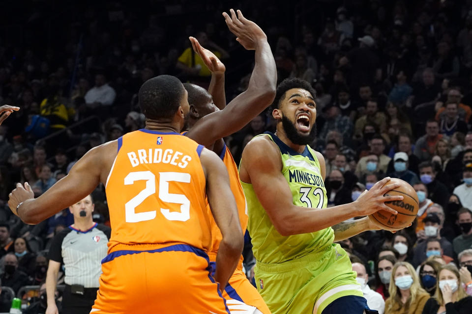 Minnesota Timberwolves center Karl-Anthony Towns (32) drives as Phoenix Suns forward Mikal Bridges (25) defends during the first half of an NBA basketball game, Friday, Jan. 28, 2022, in Phoenix. (AP Photo/Matt York)