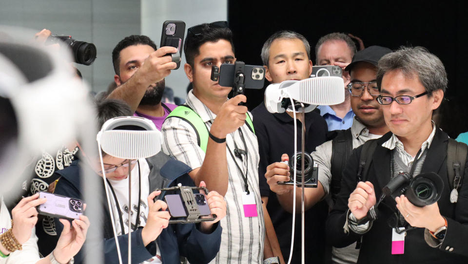 Loads of people with their phones out while crowding around the Apple Vision Pro