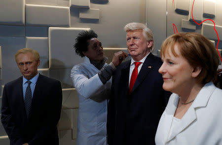 A technician works on a waxwork of U.S. President-elect Donald Trump (C), which is presented between waxworks of Russia's President Putin and Germany's Chancellor Merkel, at the Musee Grevin in Paris, France, January 19, 2017. REUTERS/Philippe Wojazer