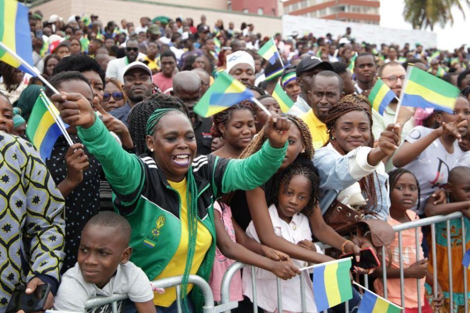 Residents wave flags during a military parade for Gabon Independence Day.