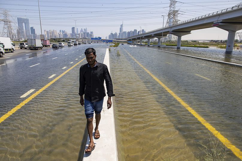 A man walks on a roadblock amid flood water caused by heavy rain on the Sheikh Zayed Road highway in Dubai.
