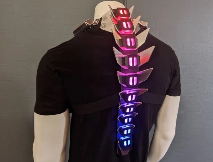 A multi-colored glowing metal spine worn on top of a black t-shirt