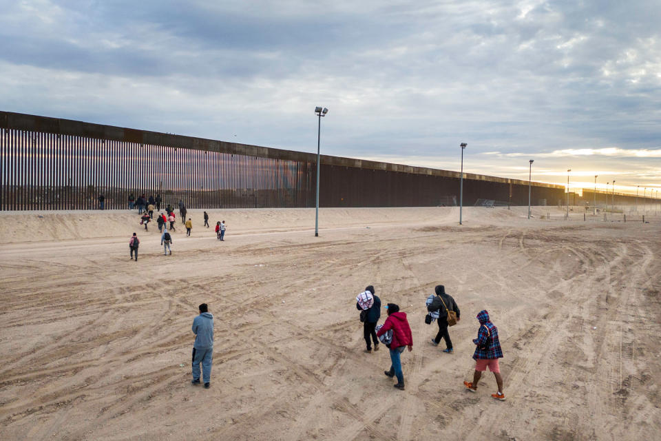 Group of immigrants walk toward the border wall.  (John Moore / Getty Images)