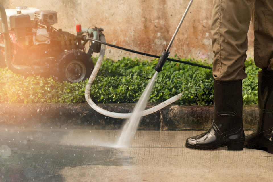 Worker cleaning driveway with gasoline high pressure washer. (Photo via Getty Images)