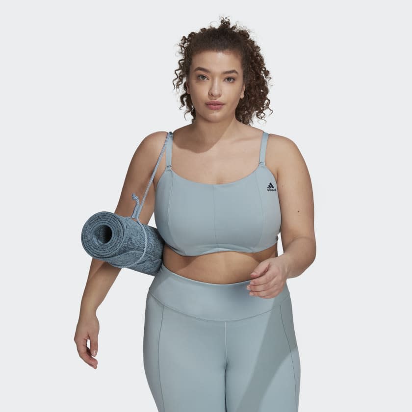 Girl wearing grey sports bra carrying yoga mat.