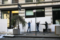 Workers board up the windows of a Chanel store Monday, June 1, 2020, following protests in the SoHo neighborhood of New York. Protests were held throughout the country over the death of George Floyd, a black man who died after being restrained by Minneapolis police officers on May 25. (AP Photo/Mark Lennihan)