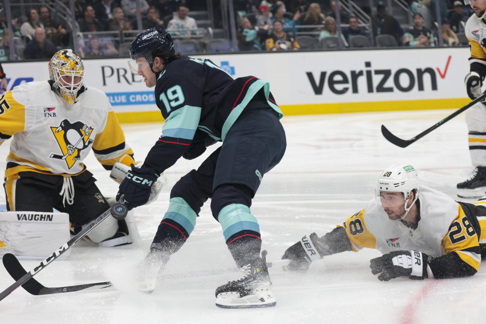 Seattle Kraken left wing Jared McCann (19) attempts to score against Pittsburgh Penguins goaltender Tristan Jarry, left, as Penguins defenseman Marcus Pettersson (28) defends during the first period of an NHL hockey game Thursday, Feb. 29, 2024, in Seattle. (AP Photo/Jason Redmond)