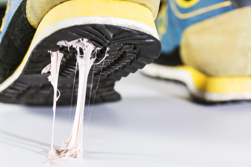 Close-up of a sneaker sole with chewing gum stuck to it, stretching as the person lifts their foot