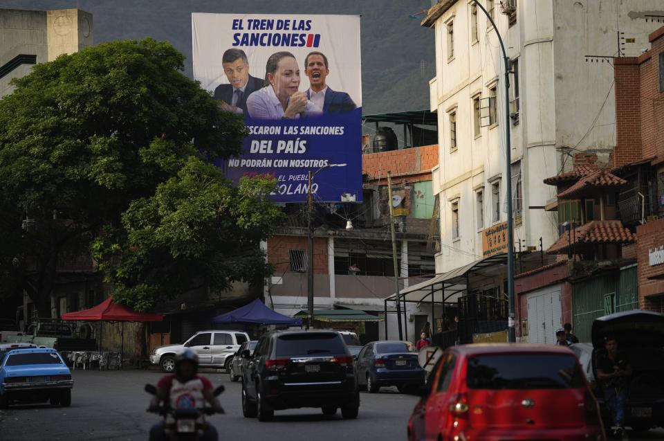 A billboard featuring Venezuelan oppositions leaders; Leopoldo Lopez, left, María Corina Machado and Juan Guaido, accompanied with a message that accuses the trio of seeking the economic U.S. sanctions, towers over a street in Caracas, Venezuela, Wednesday, May 15, 2024. (AP Photo/Ariana Cubillos)