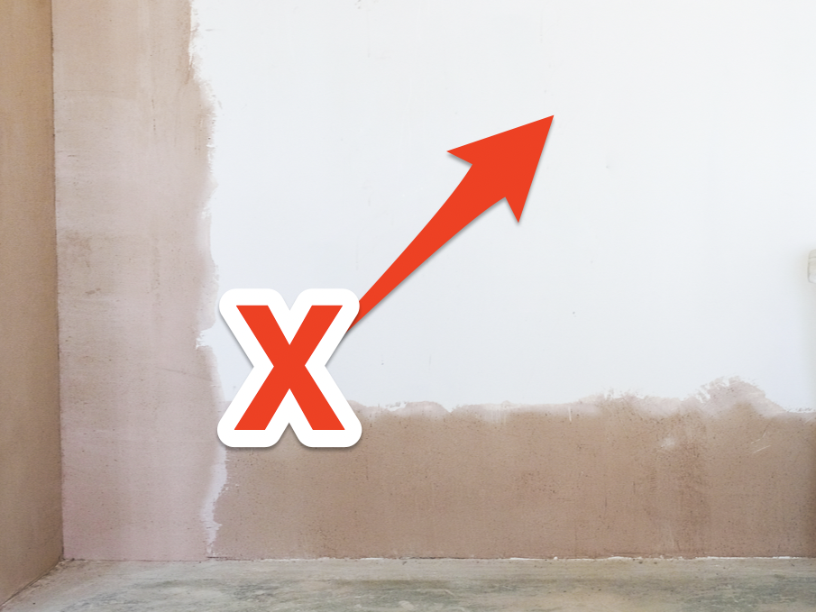 Brown wall with center painted over with white paint and white stool in front to the right. Red X and arrow pointing to white painted part of wall