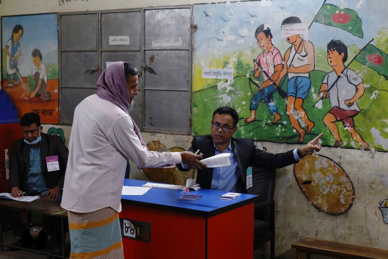 An officer instructs a voter to go to a designated area to cast vote during the 12th general election in Dhaka