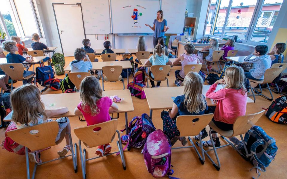 FILE - In this Monday, Aug. 3, 2020 file photo, teacher Francie Keller welcomes the pupils of class 3c of the Lankow primary school on their first school day after the summer holidays in Schwerin, Germany. Despite a spike in virus infections, European authorities are determined to send children back to school. (Jens Buettner/DPA via AP, file) - Jens Buettner/DPA