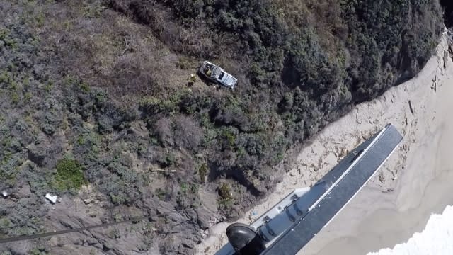 A car hangs on the side of a cliff.