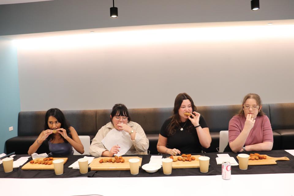 Four of Insider's reporters eating chicken wings at a table.