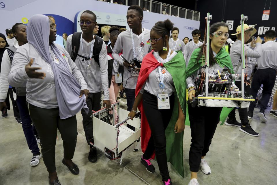 In this Friday, Oct. 25, 2019 photo, different team members carry their robots during the First Global Challenge, a robotics and artificial intelligence competition in Dubai, United Arab Emirates. Seeking to bolster its image as a forward-looking metropolis, Dubai hosted the largest-ever international robotics contest this week, challenging young people from 190 countries to find solutions to global ocean pollution. (AP Photo/Kamran Jebreili)