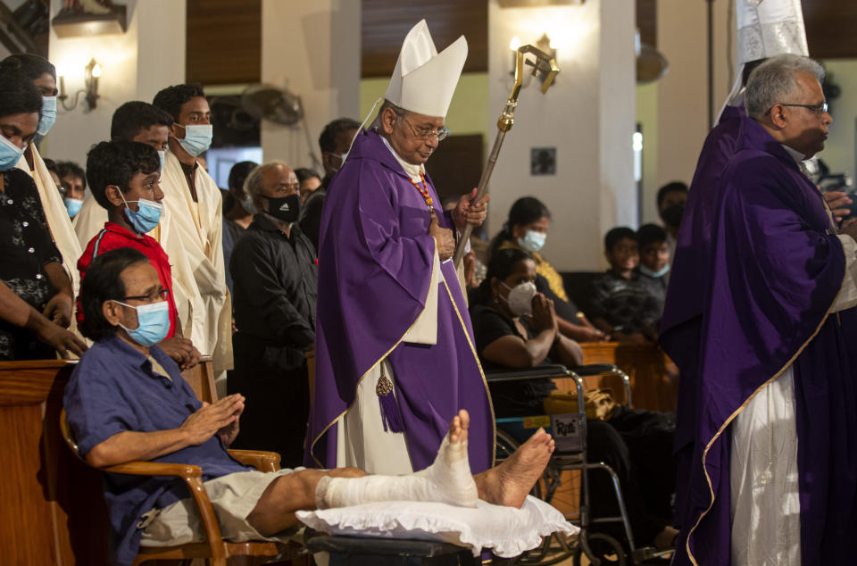 Cardinal Malcolm Ranjith, archbishop of Colombo, center, looks at a survivor of 2019 Easter Sunday attacks as he arrives to conduct a service at St. Anthony's Church in Colombo, Sri Lanka, Wednesday, April 21, 2021. Wednesday marked the second anniversary of the serial blasts that killed 269 people. (AP Photo/Eranga Jayawardena)