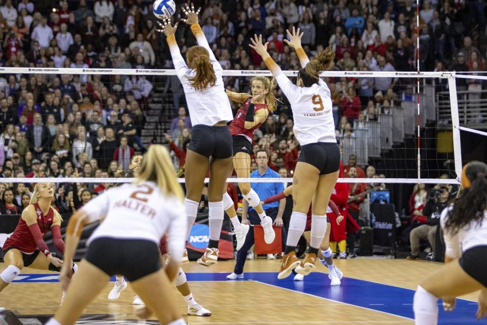 Louisville's Claire Chaussee spikes the ball against Texas' Asjia O'Neal and Saige Ka'aha'aina-Torres during the third set Saturday night. The Longhorns had to rally late in the set to close out the match and secure the national championship.