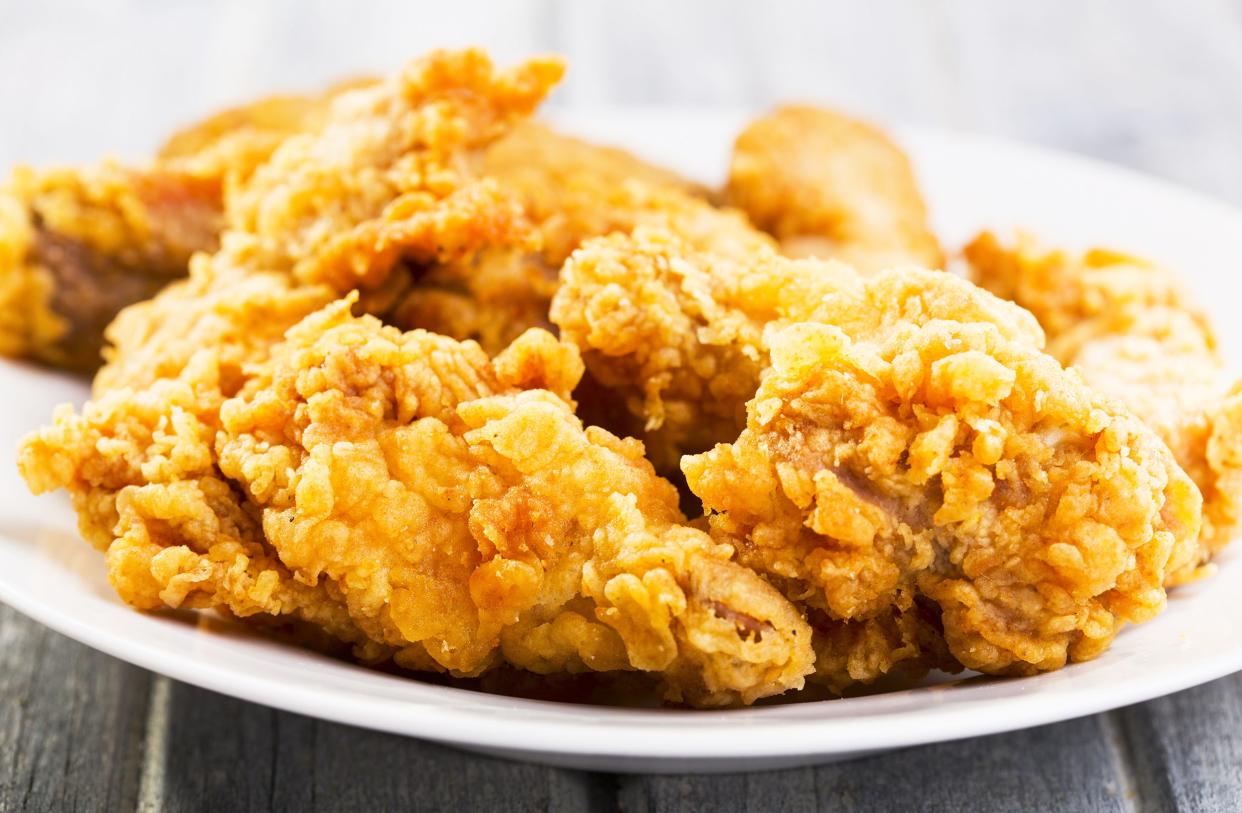 Closeup of skillet-fried chicken on a white plate on a grey wooden table